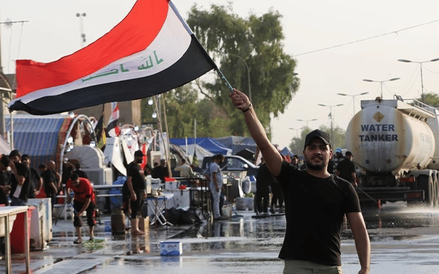 protester wields an Iraqi flag during protests